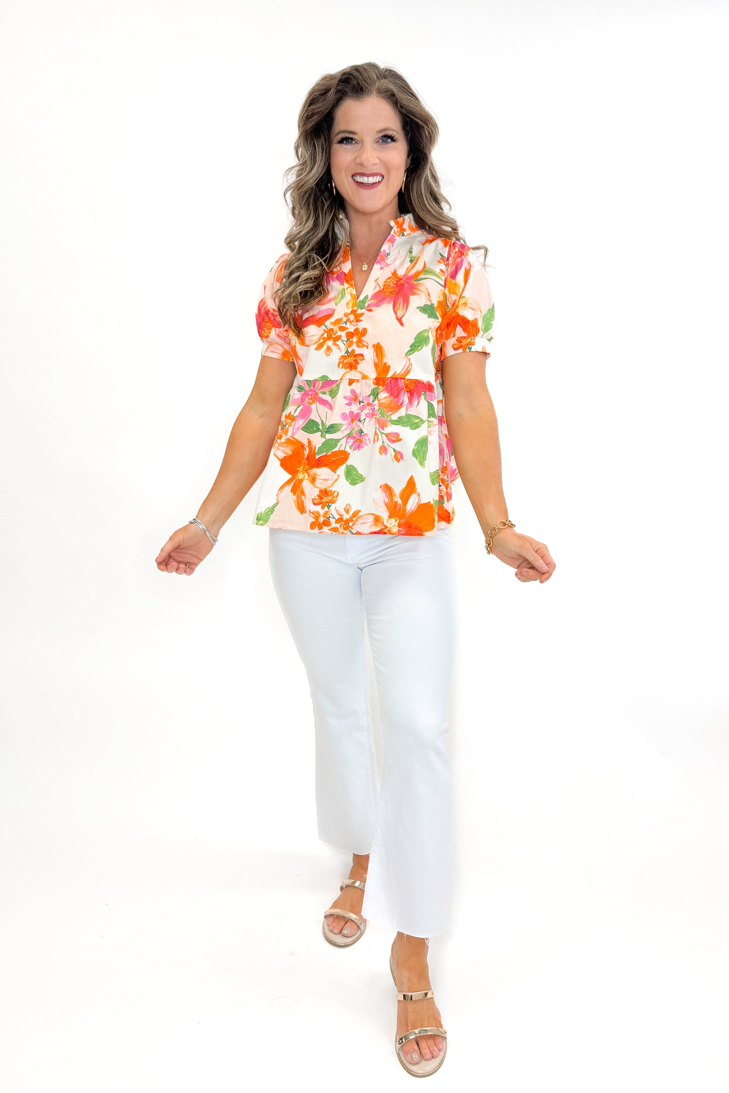 Front view of woman wearing Orange &amp; Multi Floral Peplum Top by Fate with white jeans against white studio background.
