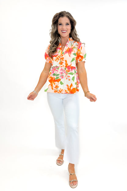 Front view of woman wearing Orange &amp; Multi Floral Peplum Top by Fate with white jeans against white studio background.