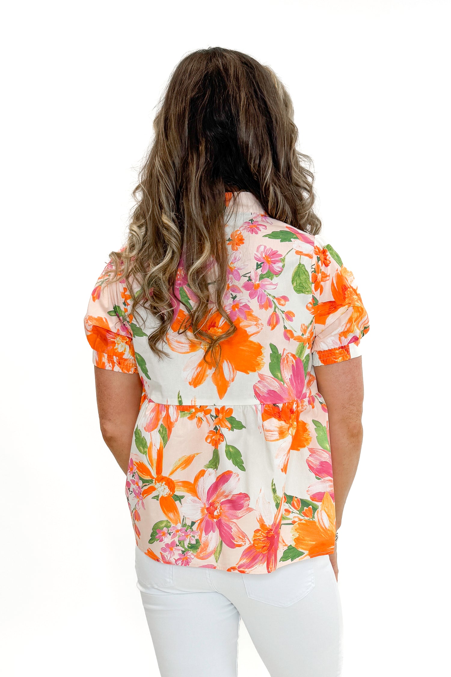 Back view of woman wearing Orange &amp; Multi Floral Peplum Top by Fate with white jeans against white studio background.
