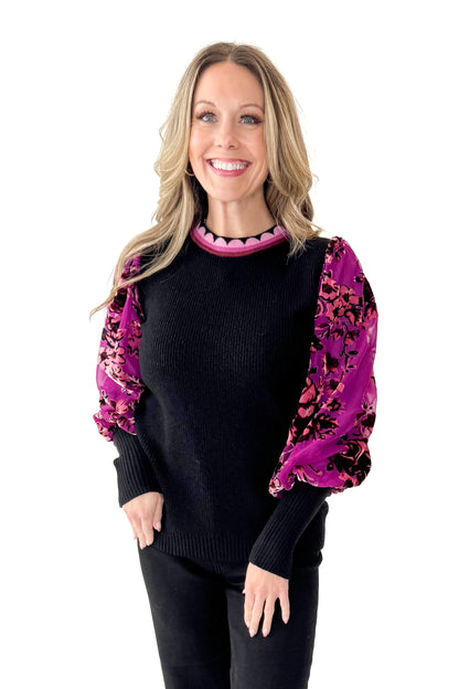 Woman wearing a black sweater with a colorful floral sleeves in front white background