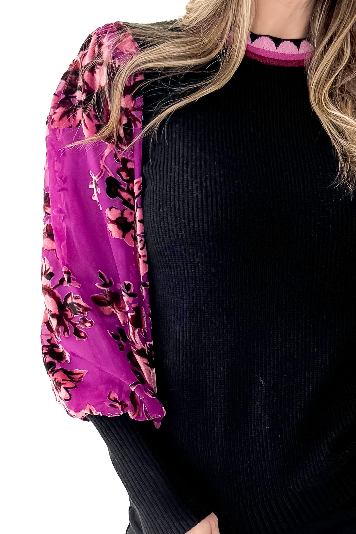 Woman wearing a black sweater with a colorful floral sleeves in front white background