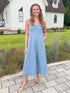 Front view of woman wearing Swagger Boutique’s Denim Floral Textured Midi Dress with sandals walking down a path.