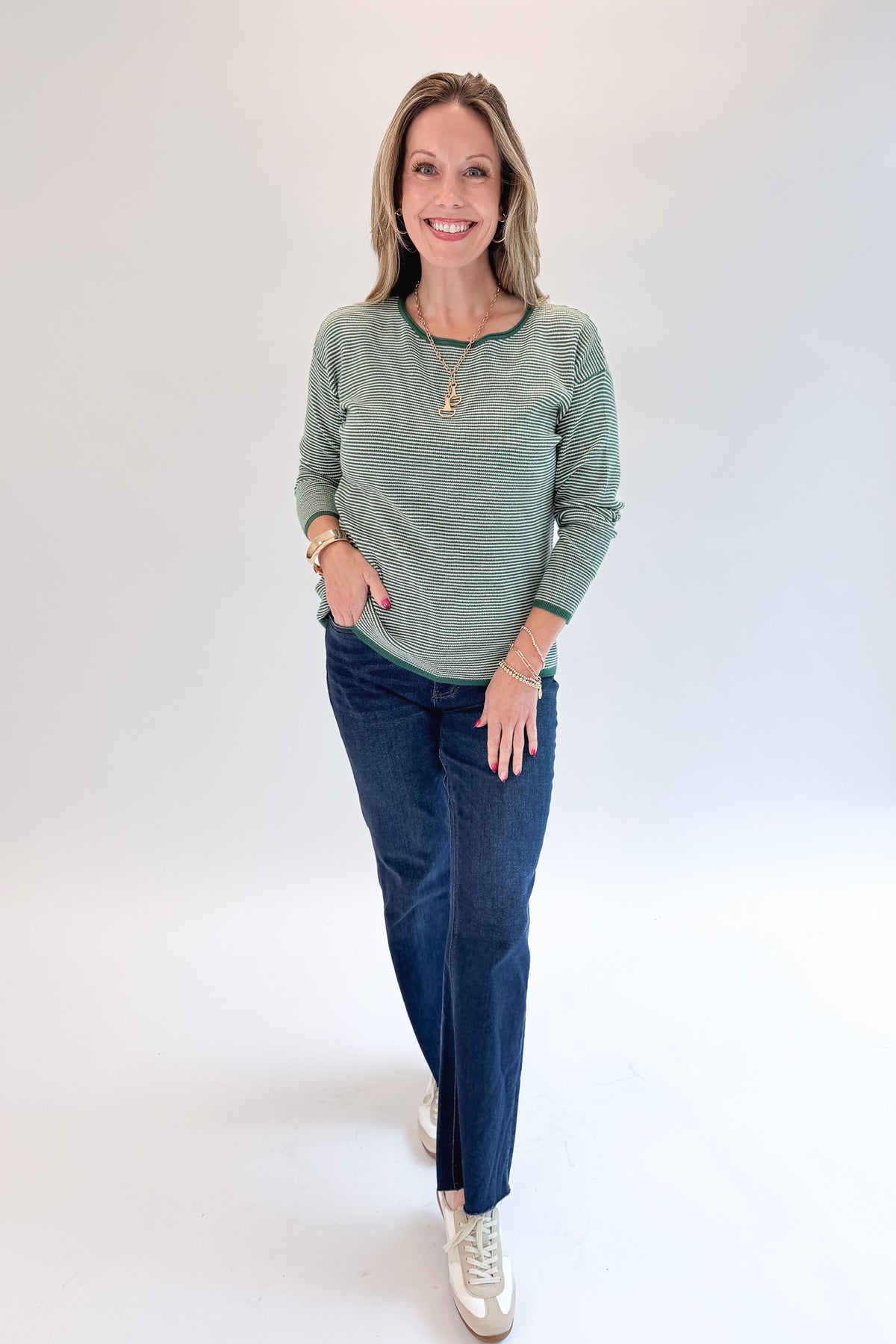 Front view of woman wearing Swagger Boutique’s Forest Green Striped Sweater with jeans against white studio background.