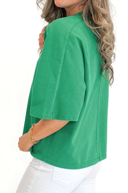 Side view of woman wearing Green Washed Boxy Tee with jeans against white studio background.
