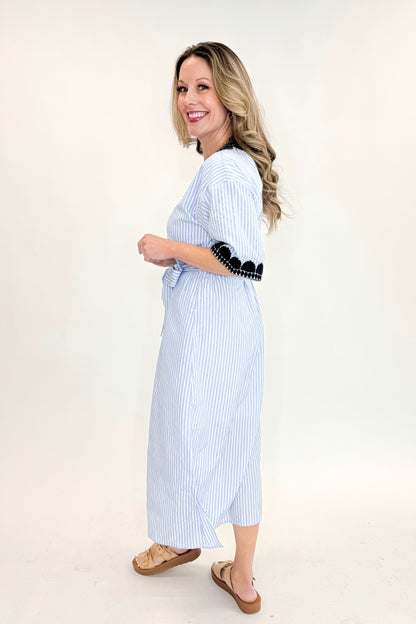 Side view of woman wearing Blue Striped Embroidery Accent Midi Dress with sandals against white studio background.
