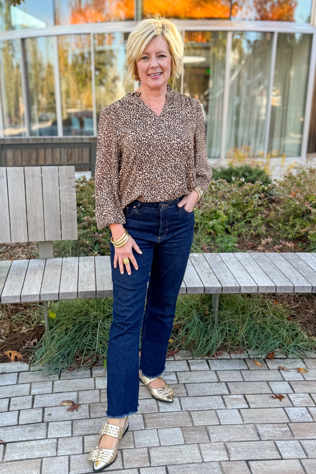 Front view of woman wearing Leopard V-neck With Metallic Detail Top with jeans outside.