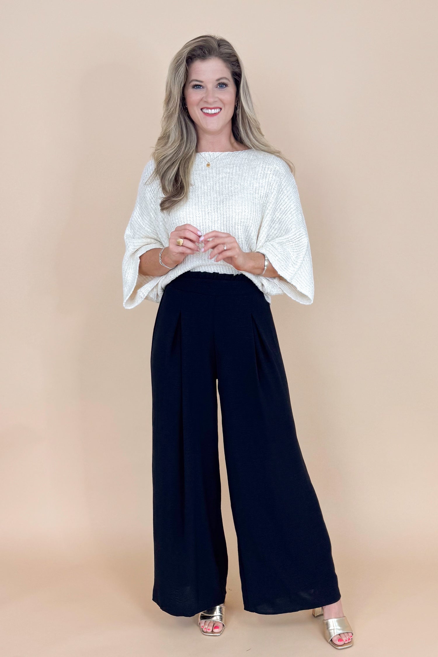 Woman wearing a white blouse and black pants on a beige background