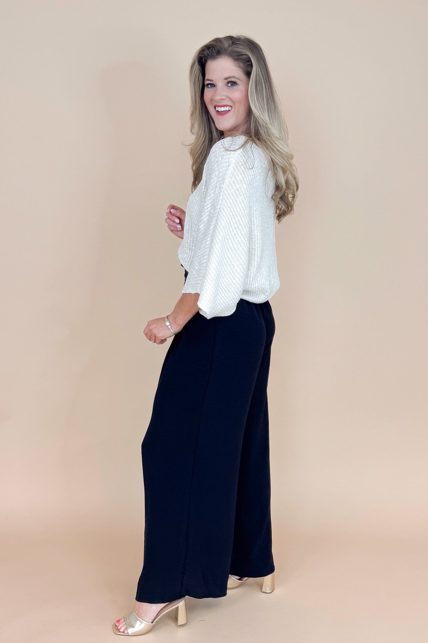 Woman wearing a white blouse and black pants on a beige background