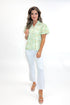 Front view of woman wearing Green & Yellow Floral Eyelet Top with white jeans against white studio background.