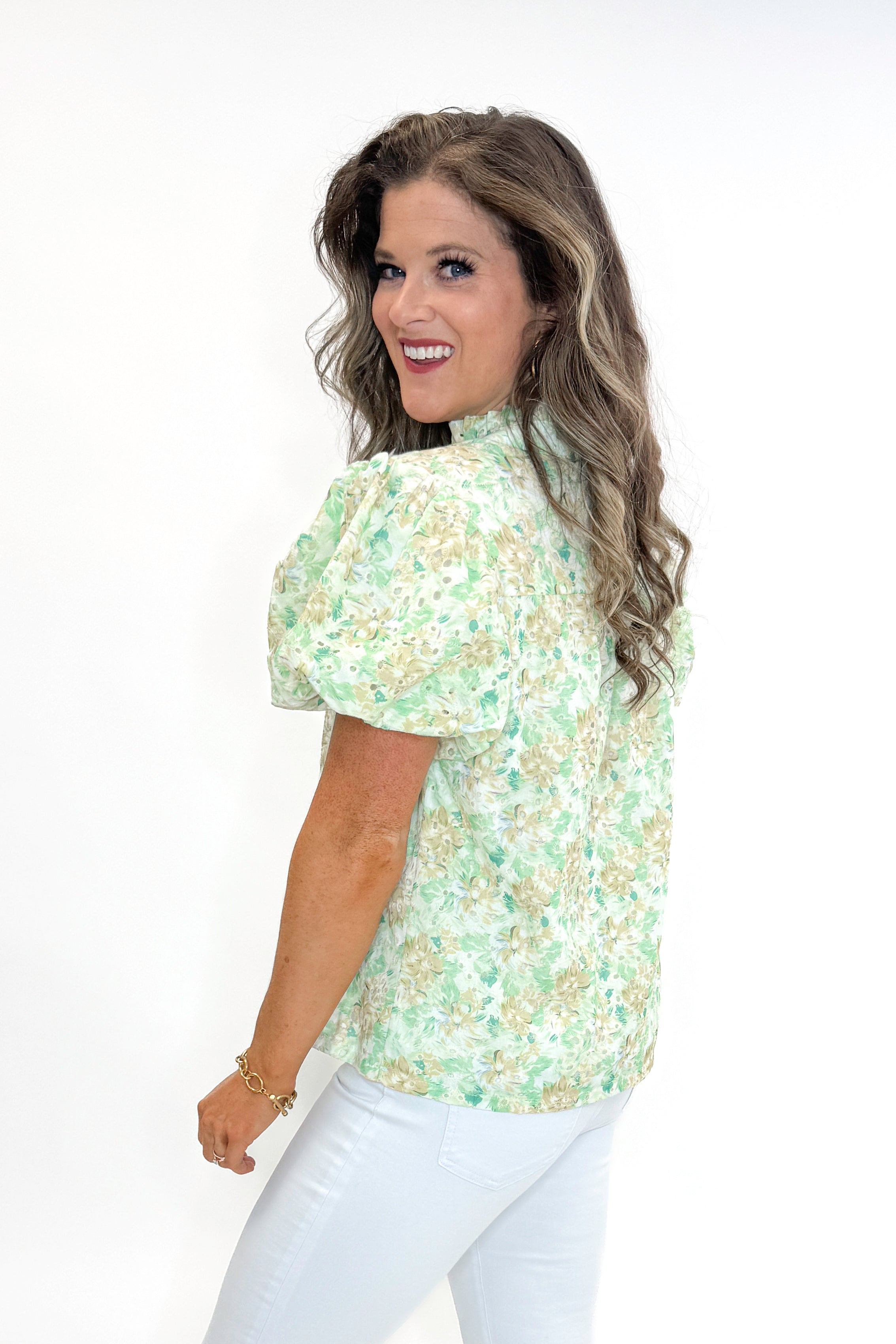Side view of woman wearing Green &amp; Yellow Floral Eyelet Top with white jeans against white studio background.