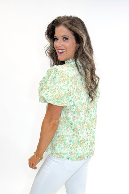 Side view of woman wearing Green &amp; Yellow Floral Eyelet Top with white jeans against white studio background.