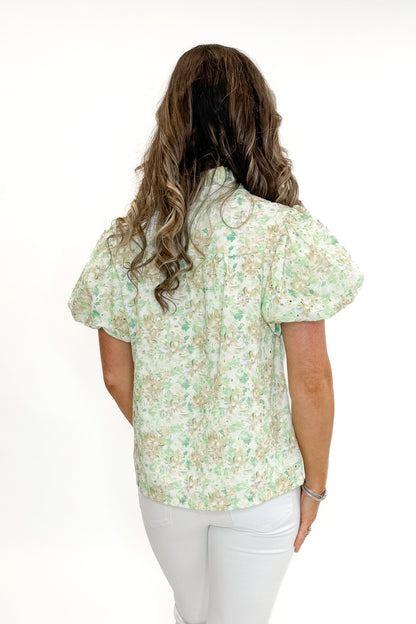 Back view of woman wearing Green &amp; Yellow Floral Eyelet Top with white jeans against white studio background.