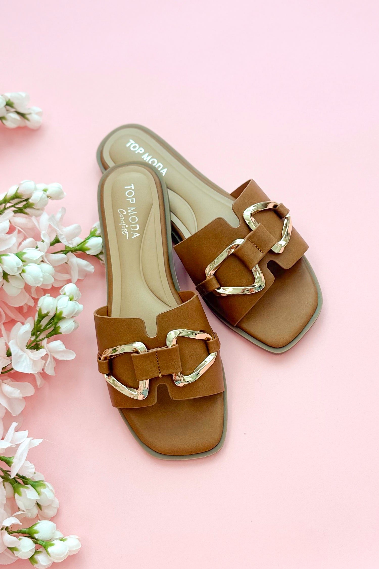 Top view of Gelato- Tan Buckle Detail Sandals against pink studio background.