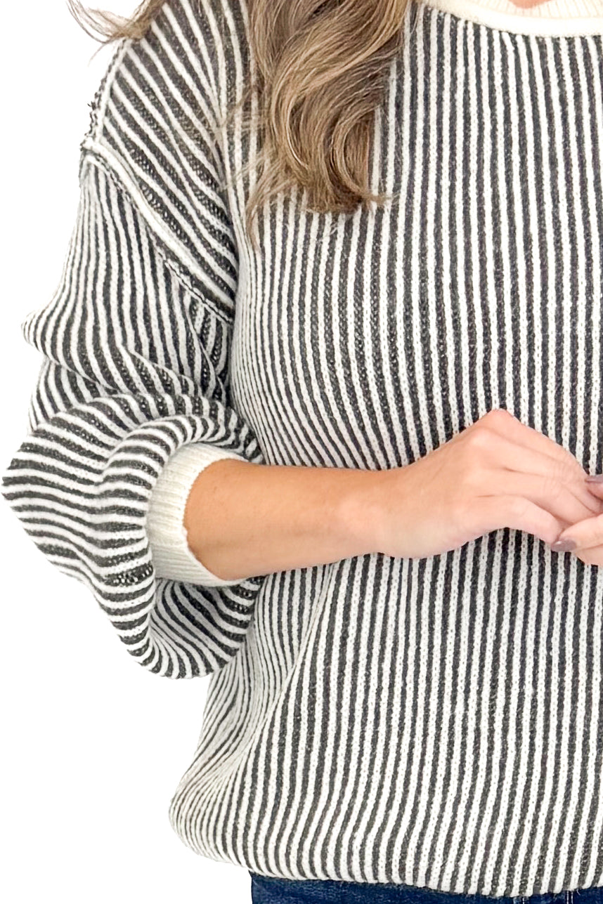 Detailed view of woman wearing Cream and Charcoal Striped Sweater against white studio background.