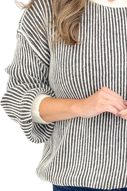 Detailed view of woman wearing Cream and Charcoal Striped Sweater against white studio background.
