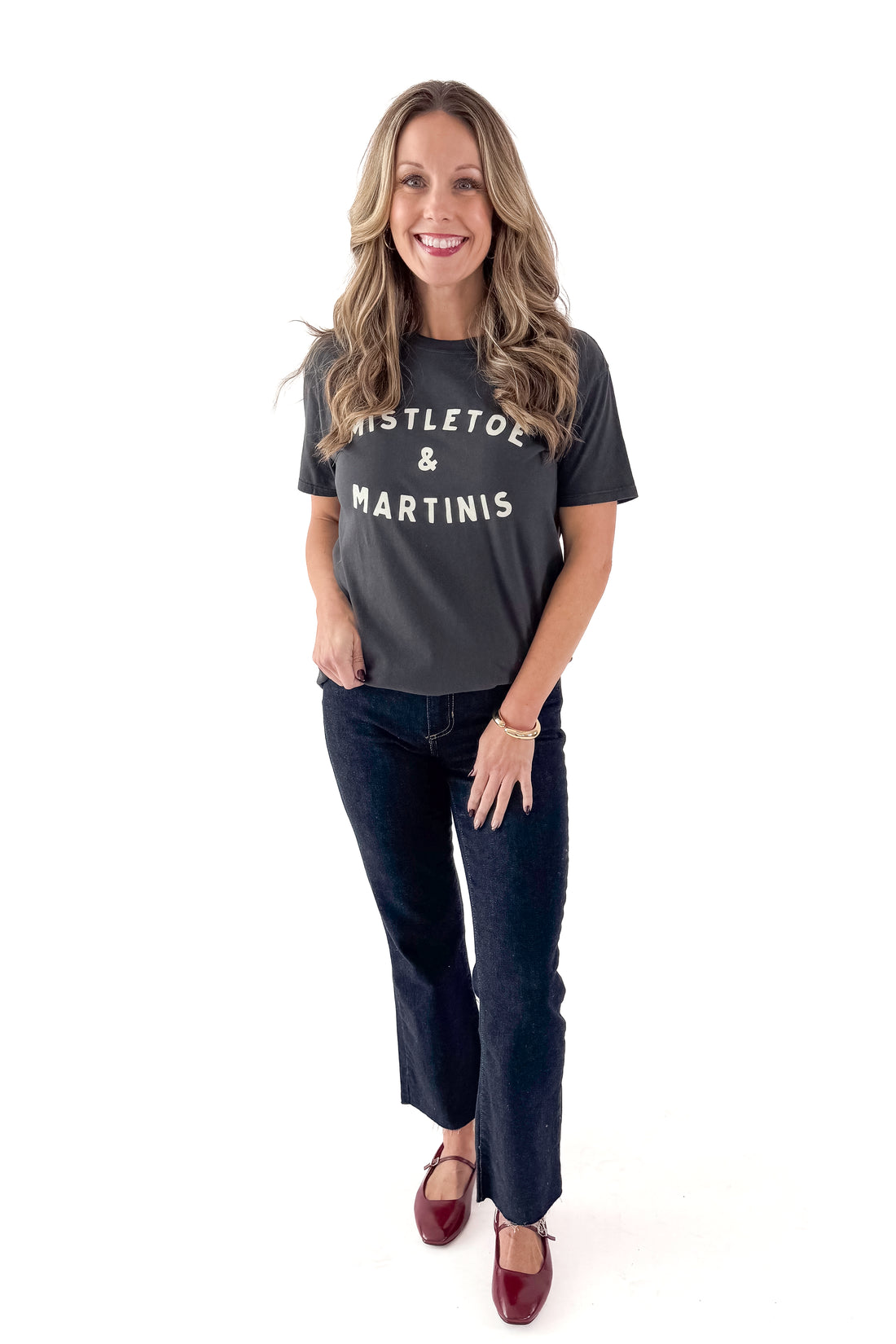 Front view of woman wearing Mistletoe Z Supply tee with jeans against white studio background.