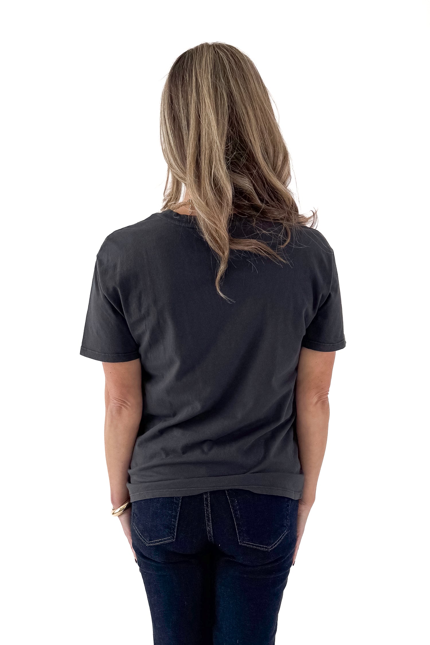 Back view of woman wearing Mistletoe Z Supply tee with jeans against white studio background.