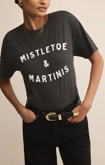 Front view of woman wearing Mistletoe Z Supply tee with jeans against tan studio background.
