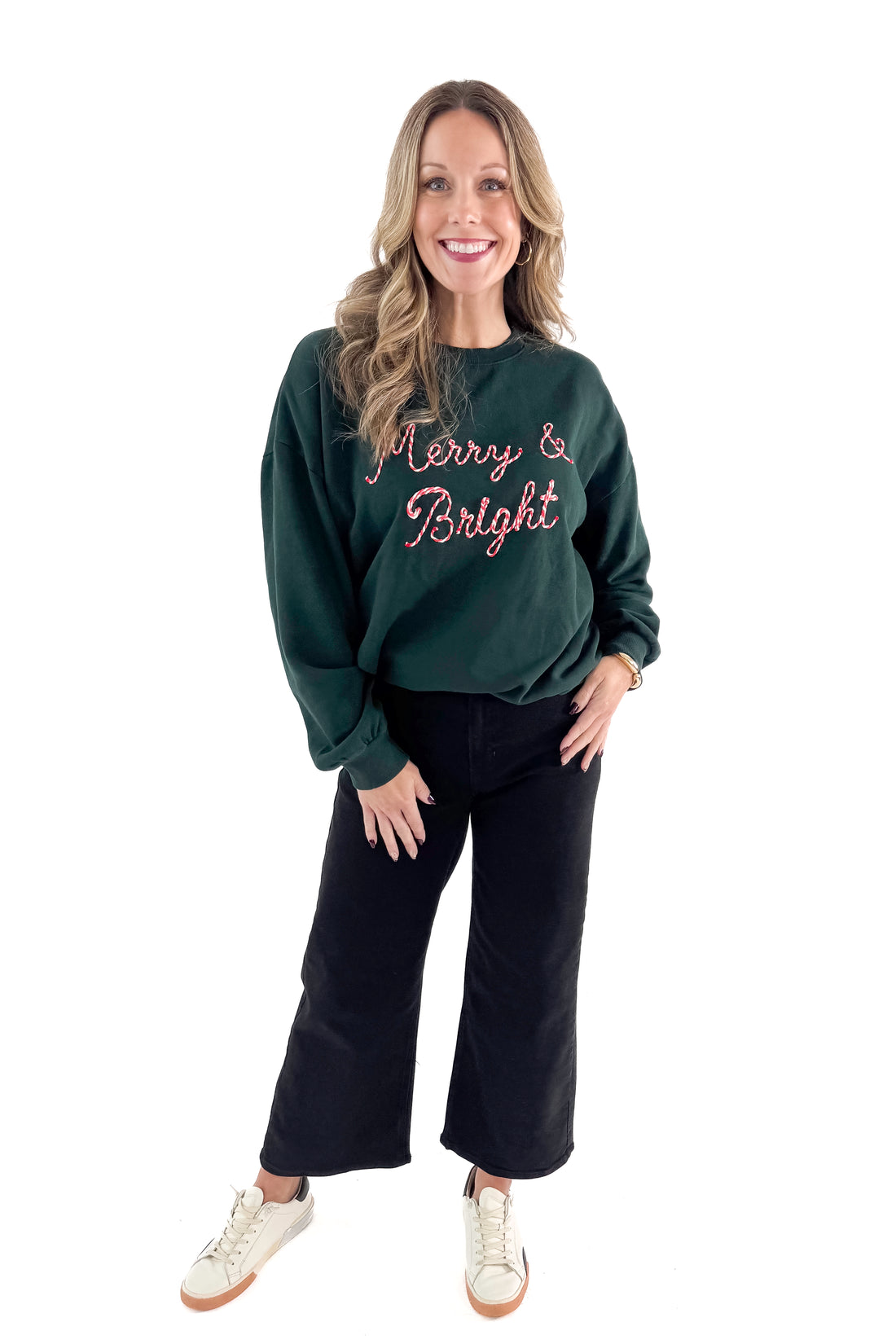 Front view of woman wearing Garland Green Bright Sunday Sweatshirt with jeans against white studio background.