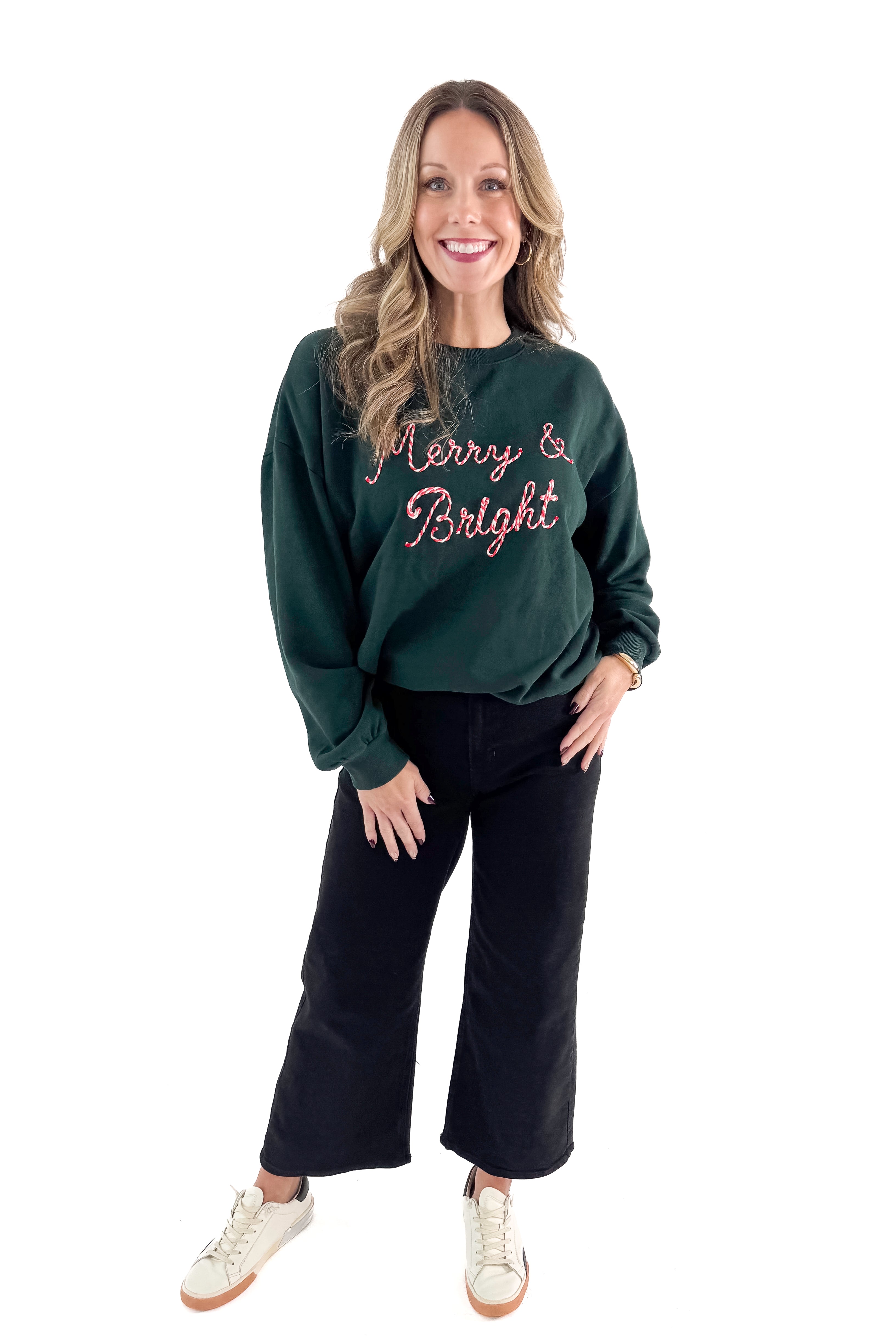 Front view of woman wearing Garland Green Bright Sunday Sweatshirt with jeans against white studio background.