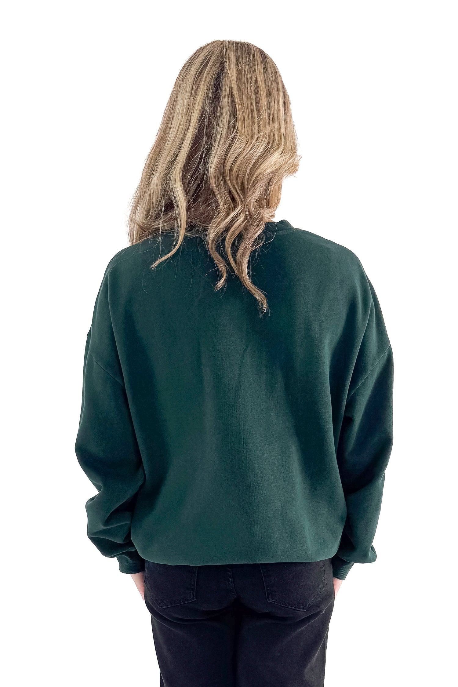 Back view of woman wearing Garland Green Bright Sunday Sweatshirt with jeans against white studio background.