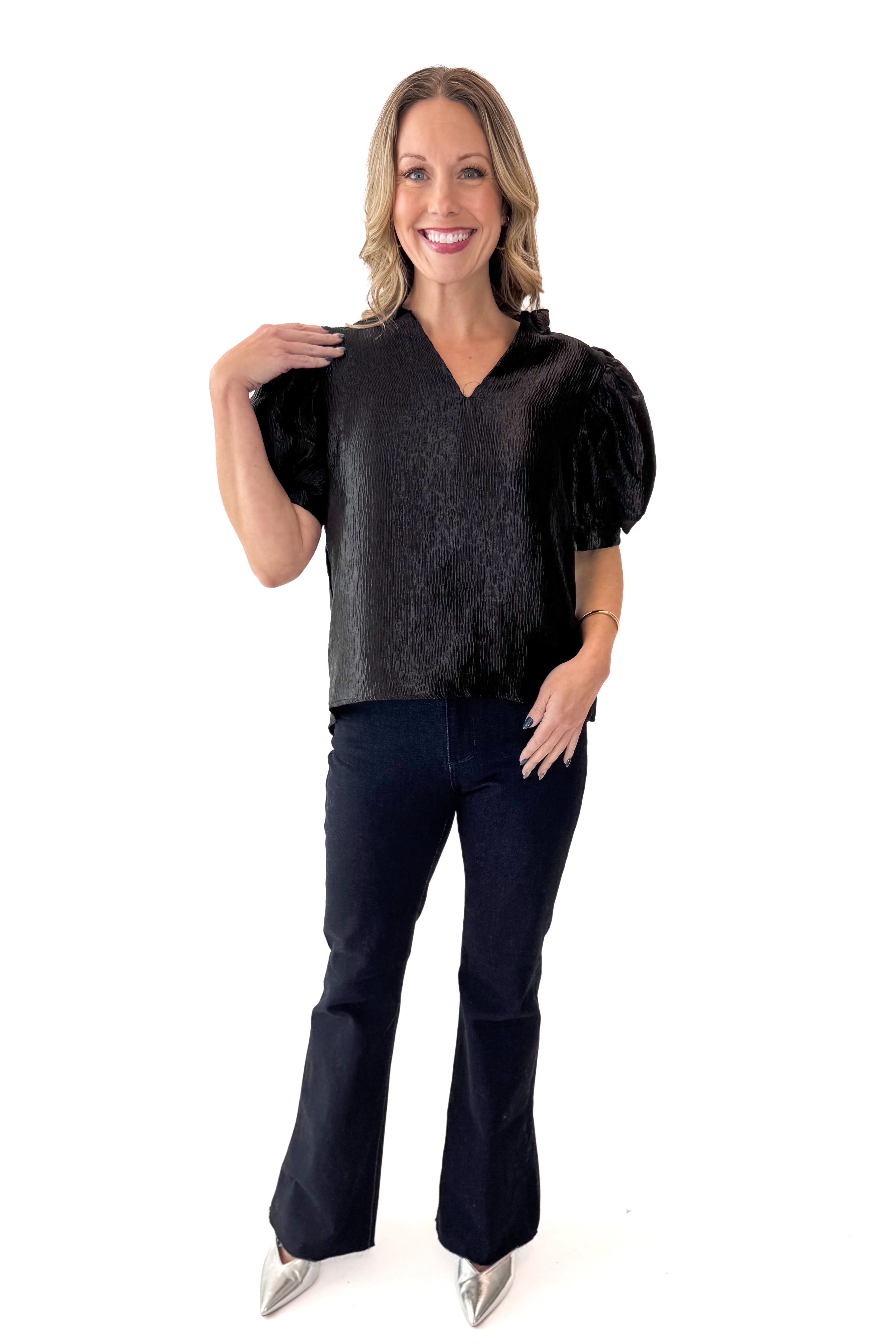 Front view of woman wearing Black Sheen Textured Puff Sleeve Top with jeans against white studio background.