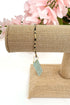Beaded bracelet on a mannequin arm with pink flowers in the background