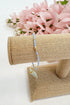 light blue bracelet on a beige jewelry display with pink flowers in the background