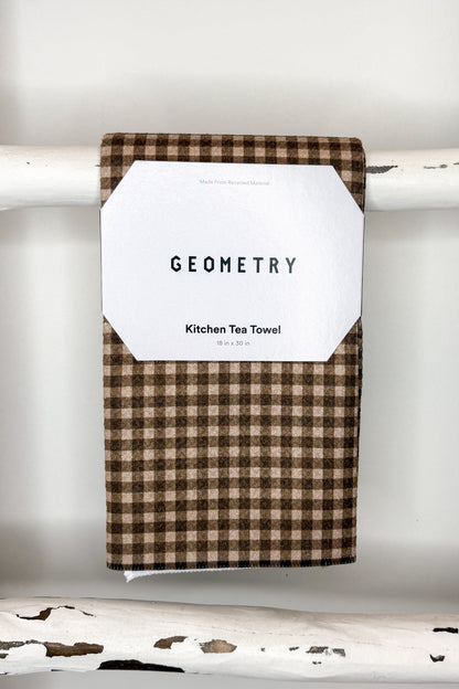 A brown and beige gingham kitchen tea towel with a white paper label that reads &
