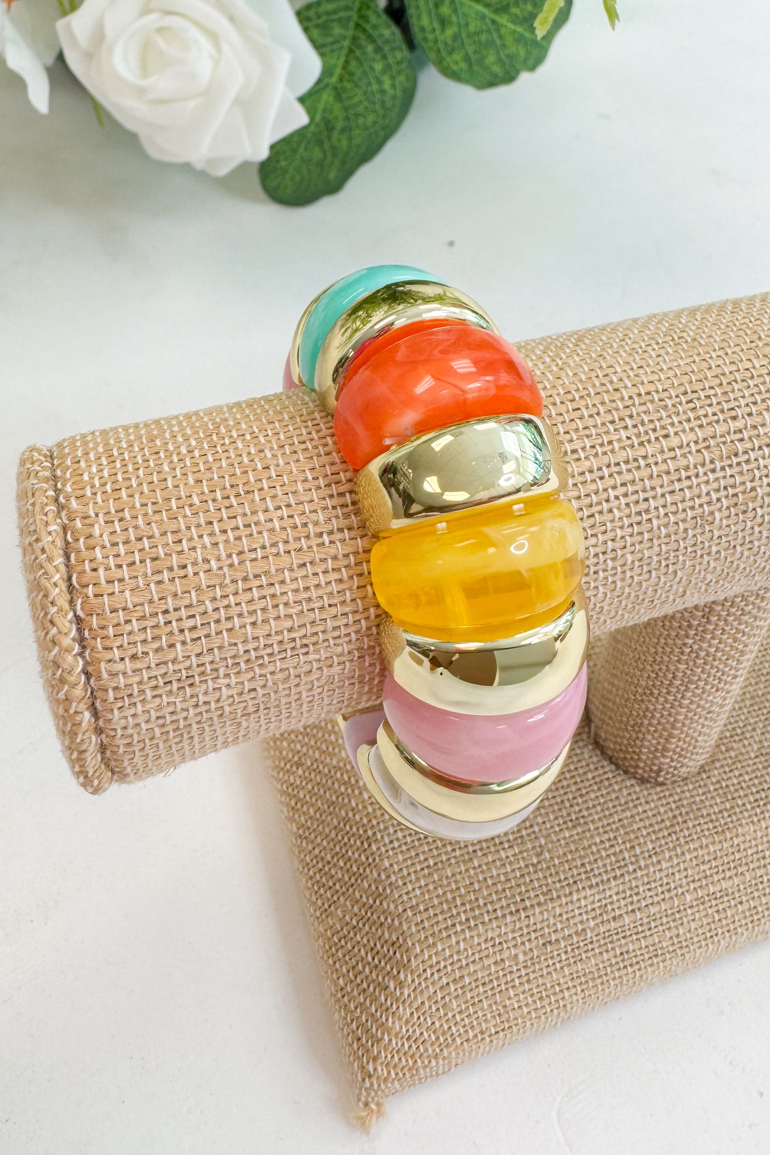 Colorful bangle on a textured surface with flowers in the background
