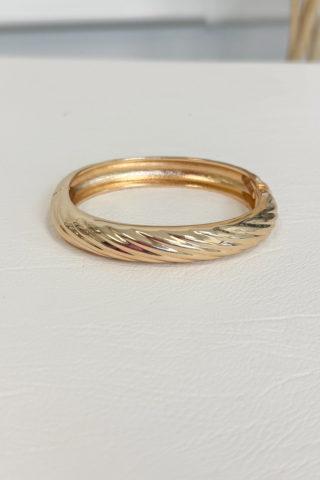 Gold-tone polished bracelet with a simple smooth, rounded band design on a white studio background