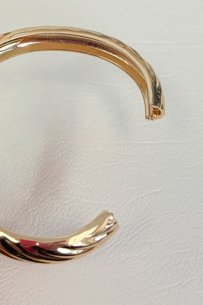Gold-tone open cuff bracelet with a smooth curved design white studio background