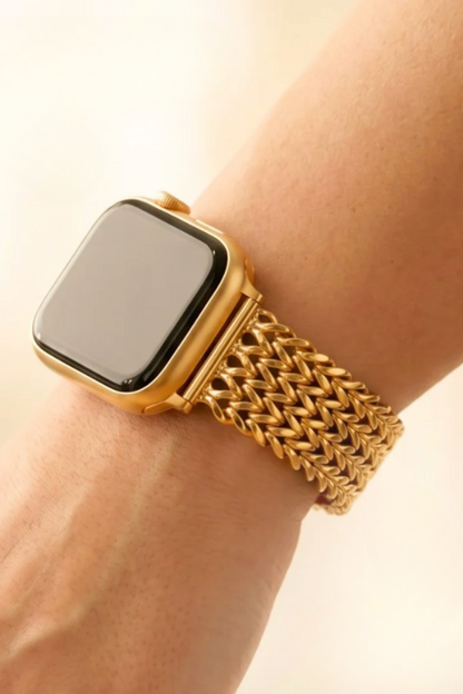 A close-up of a gold smartwatch with a woven gold mesh band worn on a person&
