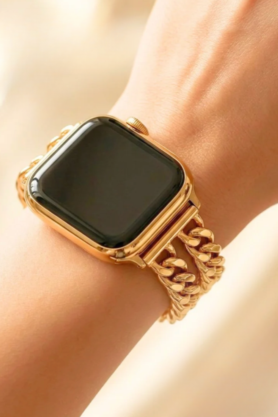 A close-up of a gold-toned smartwatch with a thick, chunky curb-link metal band worn on a person&