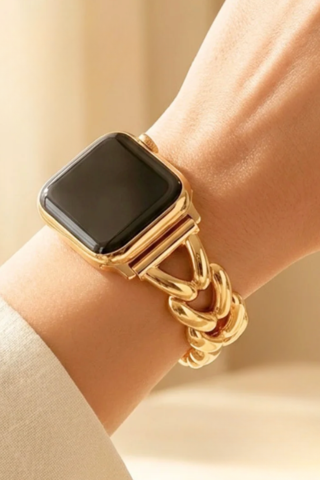 A close-up of a gold-toned smartwatch with a thick chain-link band worn on a person&