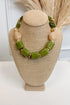 front view of green statement necklace with small gold and cream accents displayed of bust 