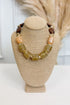 front view of chunky olive, soft peach, and brown beaded necklace with gold accents on bust