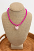 Necklace with pink beads and a heart-shaped charm on a beige bust against a white background