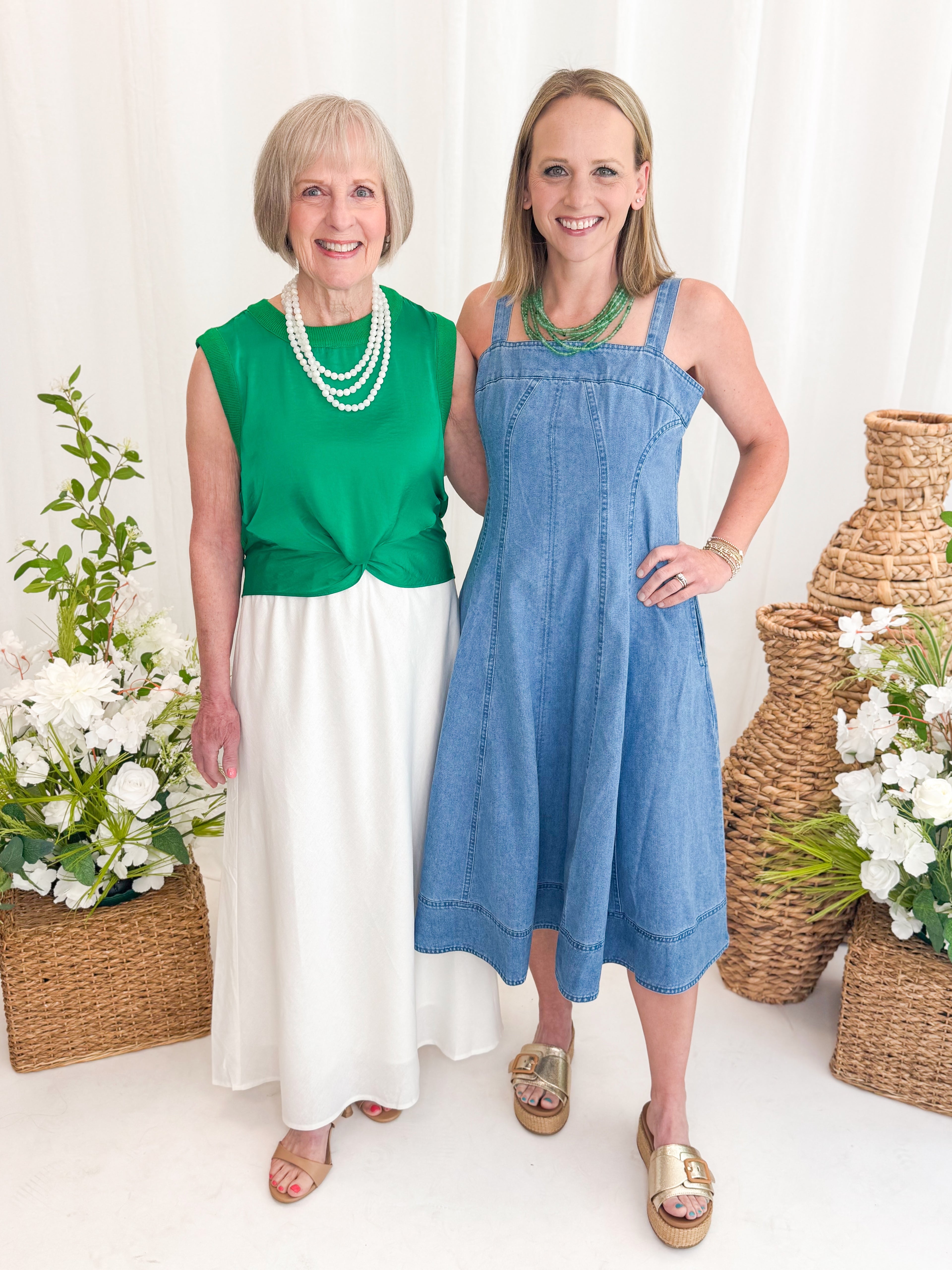Front view of woman wearing Swagger Boutique’s Green Sleeveless Tank With Twist by Skies Are Blue with white skirt with woman wearing Denim Fit &amp; Flare Midi Dress at boutique.