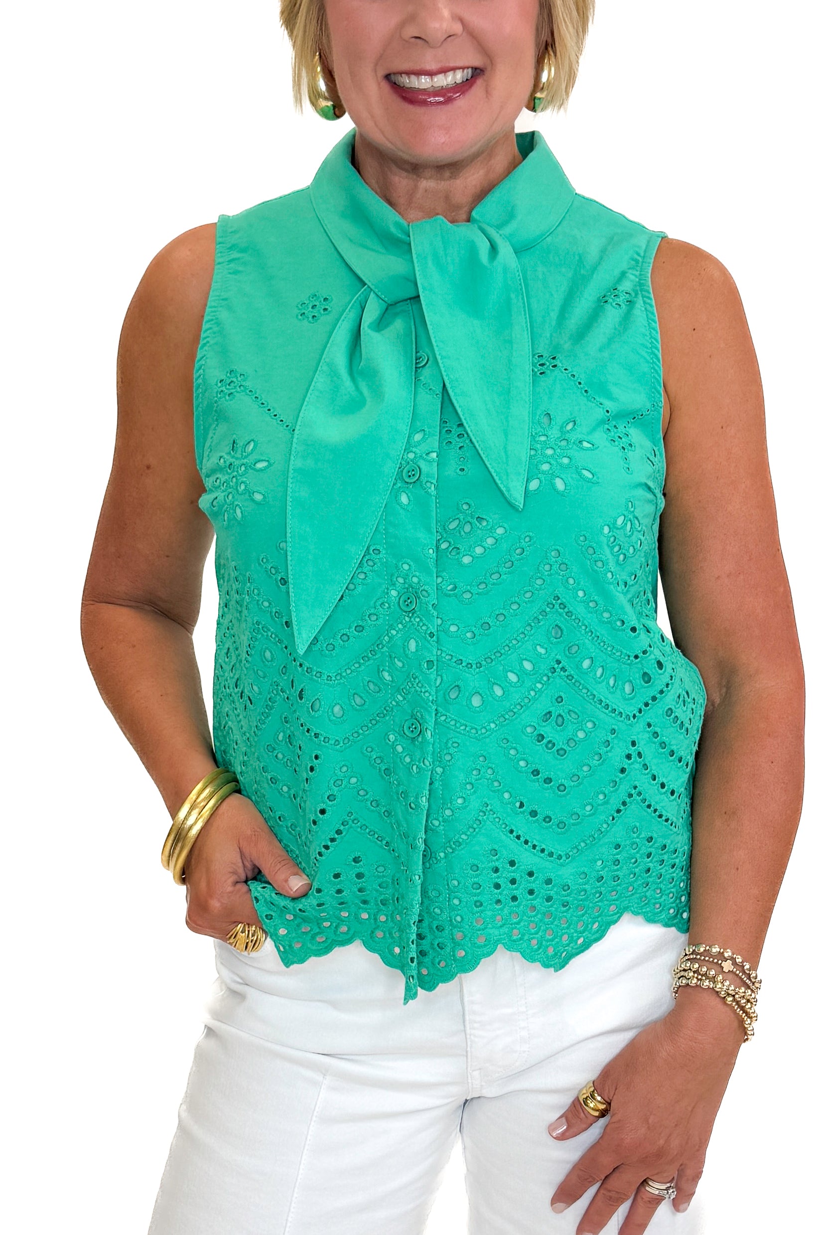 Front detail view of woman wearing Swagger Boutique’s Green Tie Neck Eyelet Sleeveless Top with jeans against white studio background.