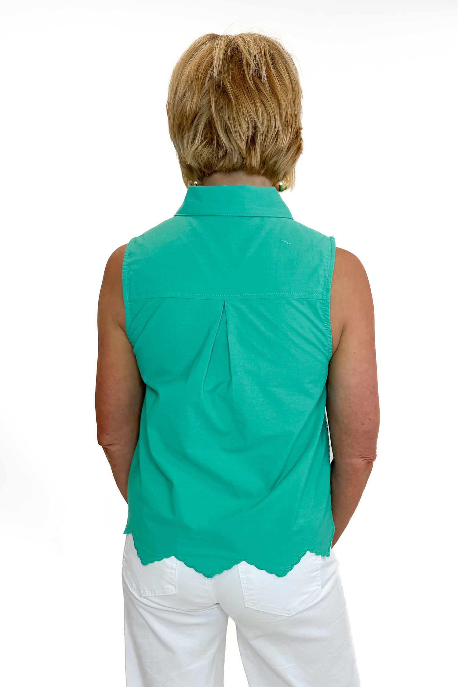 Back view of woman wearing Swagger Boutique’s Green Tie Neck Eyelet Sleeveless Top with jeans against white studio background.