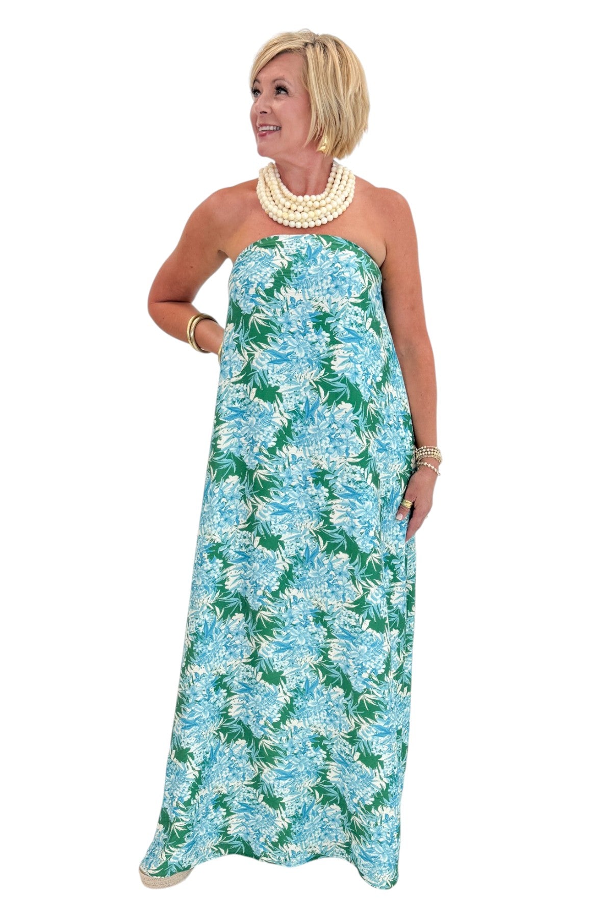Front view of woman wearing Swagger Boutique’s Green &amp; Blue Floral Print Strapless Maxi Dress by Entro with sandals against white studio background.