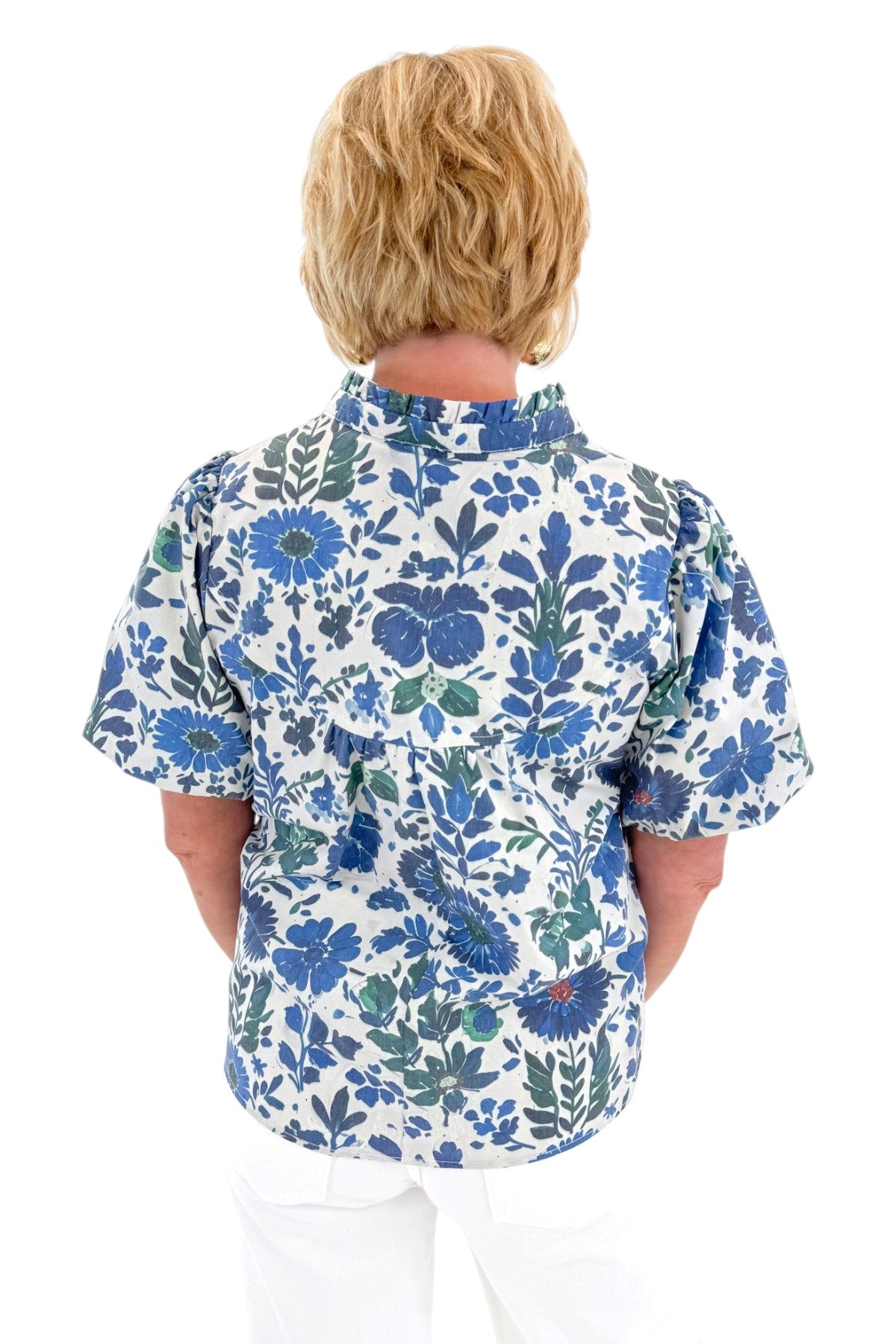Back view of woman wearing Swagger Boutique’s Green &amp; Blue Floral V-Neck Top with sandals against white studio background.