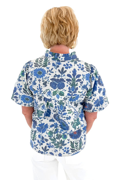 Back view of woman wearing Swagger Boutique’s Green &amp; Blue Floral V-Neck Top with sandals against white studio background.