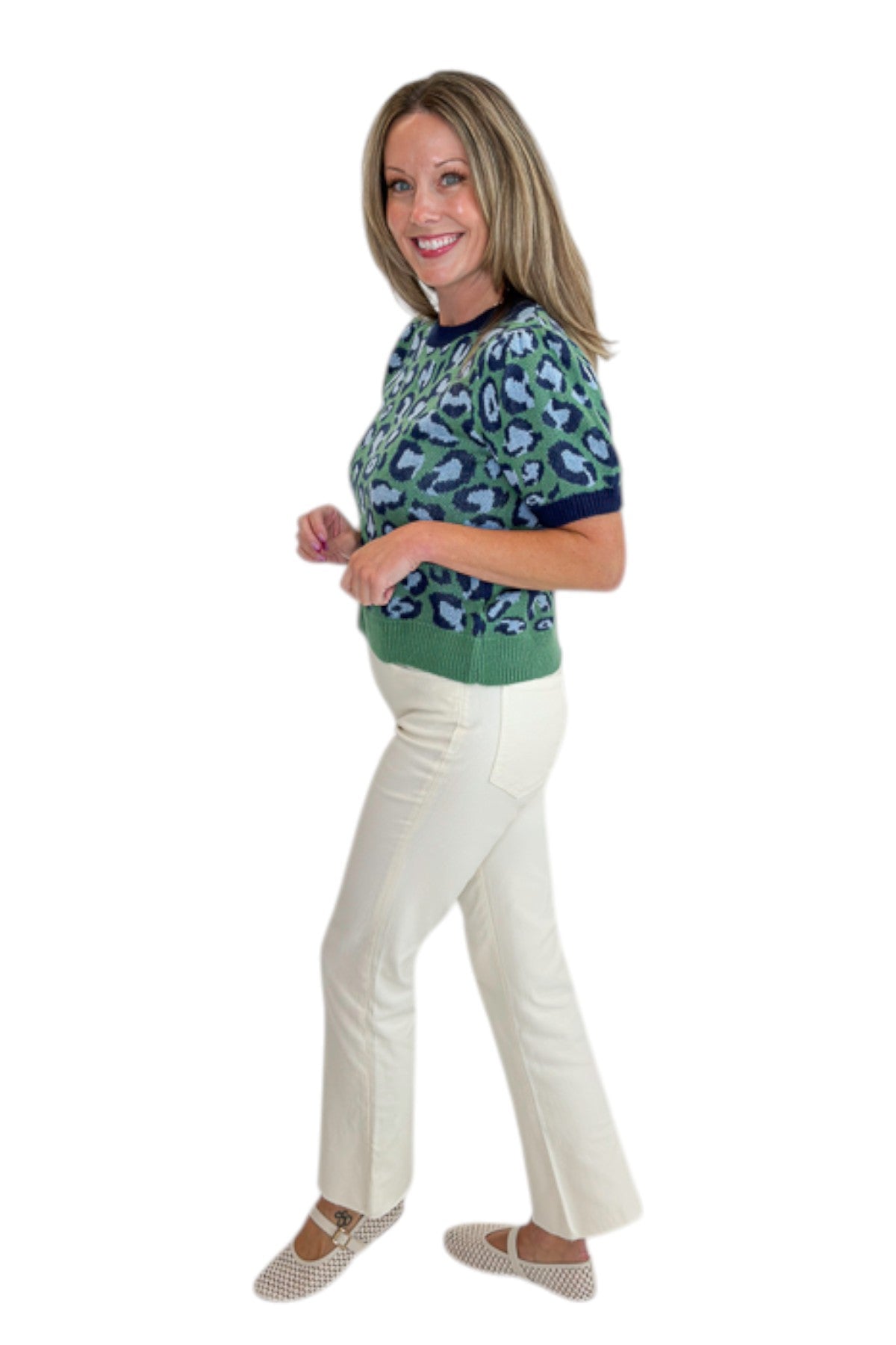 Side view of woman wearing Swagger Boutique’s Green &amp; Blue Leopard Short Sleeve Sweater with jeans against white studio background.