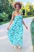 Front view of woman wearing Swagger Boutique’s Green & Blue Floral Print Strapless Maxi Dress by Entro with sandals walking outside at a park.