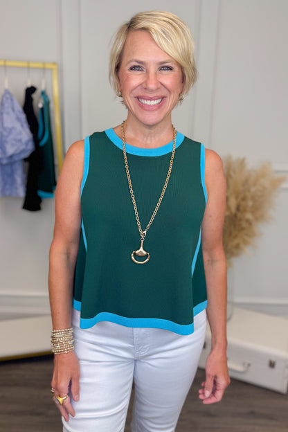 Front close up view of woman wearing a teal sleeveless sweater. 