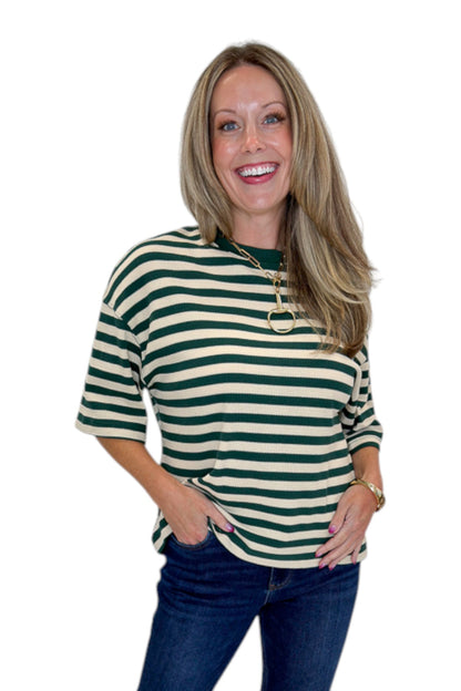 Front view of woman wearing Swagger Boutique’s Green &amp; Cream Striped Textured Tee by Entro with jeans against white studio background.