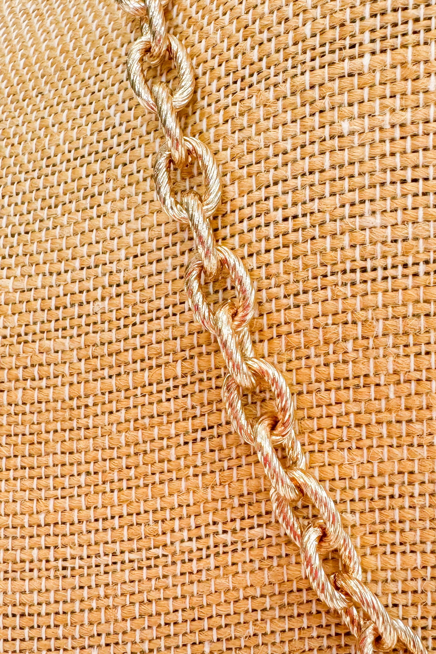 Close-up of a chain on a textured beige fabric background