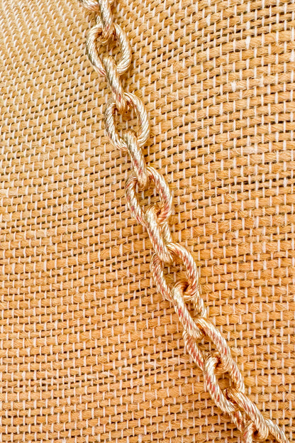 Close-up of a chain on a textured beige fabric background